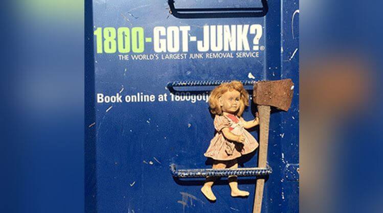 Жуткая кукла, сидящая на двери со ржавым топором