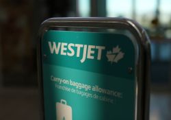 WestJet carry-on baggage allowance sign with teal background in a luggage bin area