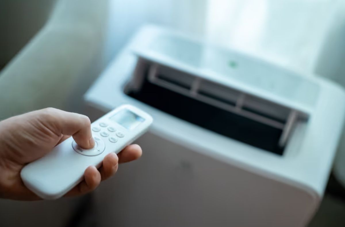 bc hydro | Наш Ванкувер Hand holding a white remote control near a white office device with an open paper feed tray (printer/shin shredder).