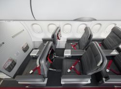 Row of gray airplane seats with red seat belts in a modern cabin interior