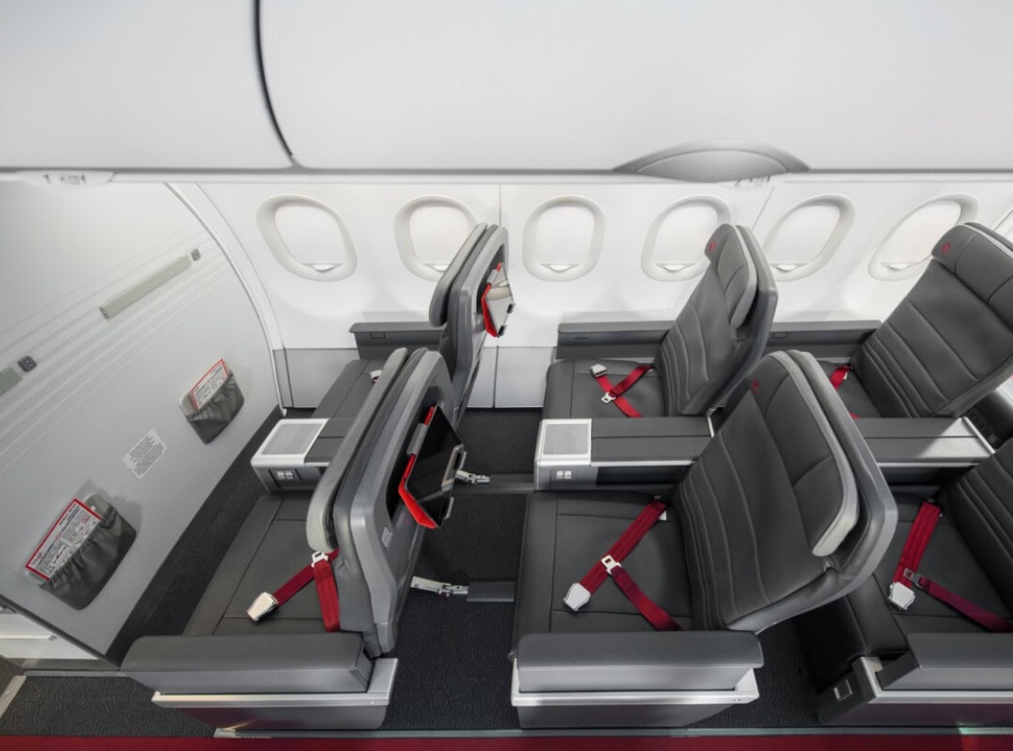 бизнесс эконом | Наш Ванкувер Row of gray airplane seats with red seat belts in a modern cabin interior