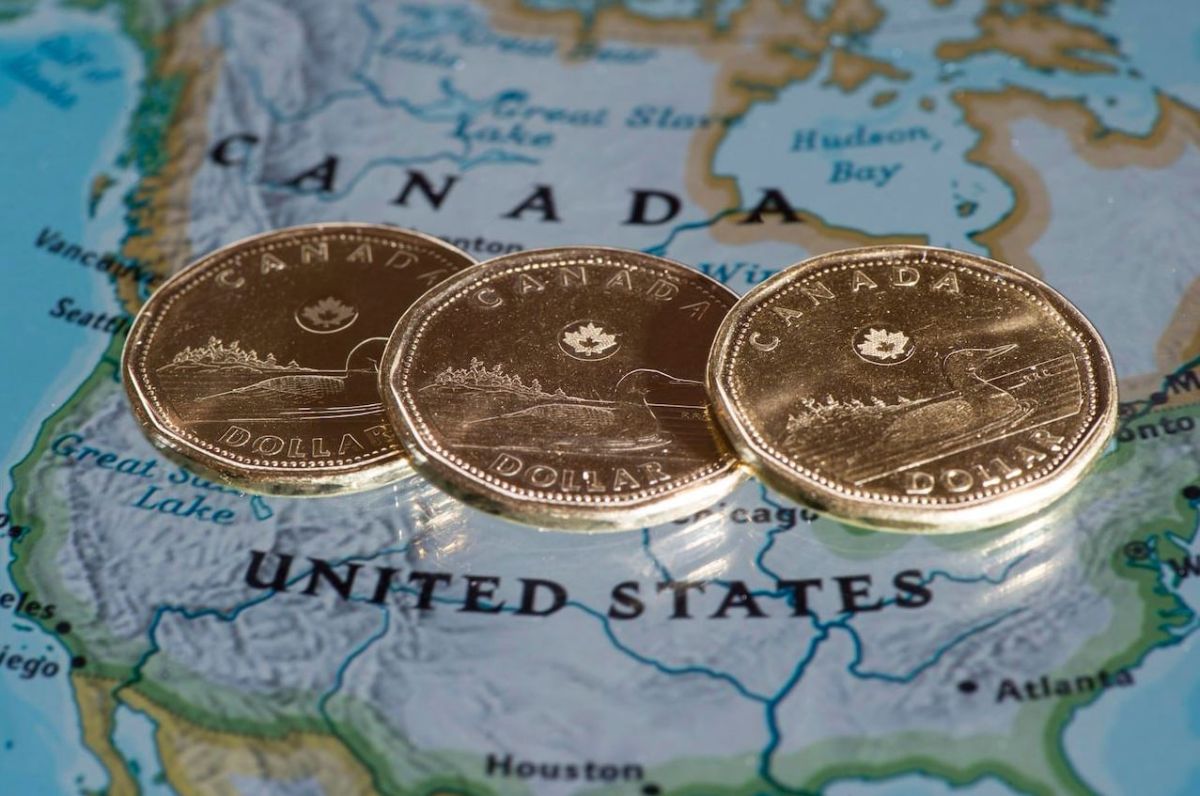 Слабость канадского доллара | Наш Ванкувер Three Canadian dollar coins lying on a map showing Canada and the United States.