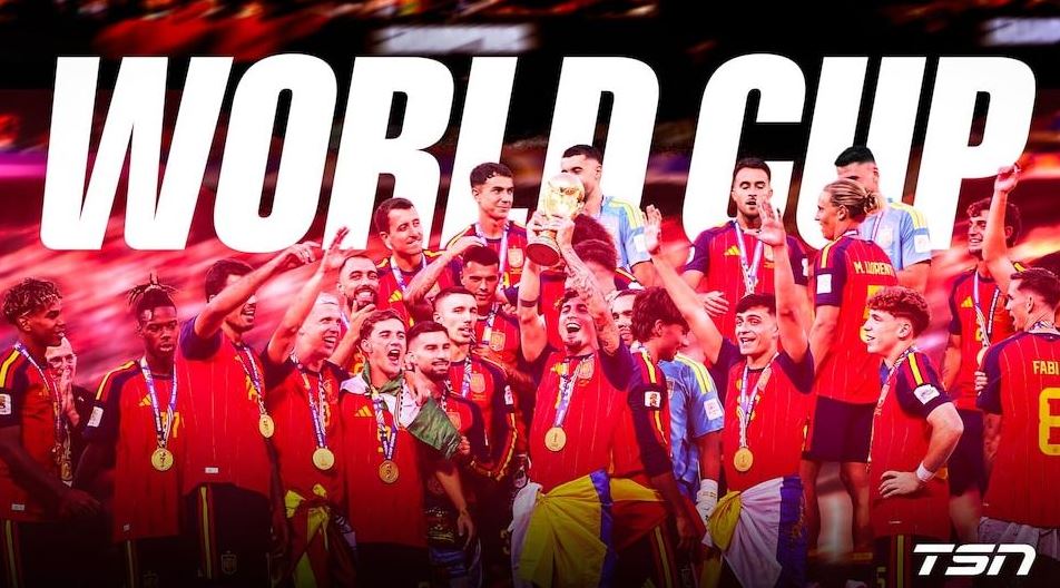 Soccer team in red uniforms celebrates with medals around their necks, some players lifting a trophy as they pose for a victory photo with 'WORLD CUP' text in the background and TSN logo bottom right.