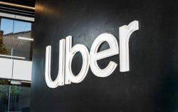White Uber logo mounted on a dark wall outside a modern office building.