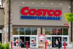 Costco Wholesale storefront with shoppers and shopping carts outside the entrance.