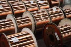 Copper wire coils on metal spools stacked in a warehouse.