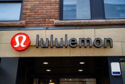 Lululemon storefront with red circular logo and bold black letters on beige facade