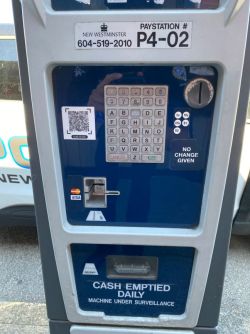 Public pay station with keypad, card slot, and QR code on blue panel; 'No change given' notice visible.