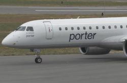 Porter Airlines airplane nose and cockpit with 'porter' logo visible on the fuselage on the taxiway edge of the runway