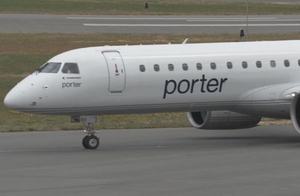 Porter Airlines airplane nose and cockpit with 'porter' logo visible on the fuselage on the taxiway edge of the runway