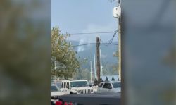 Street scene with a white SUV in the foreground, a wooden utility pole with power lines, and mountains in the distance.
