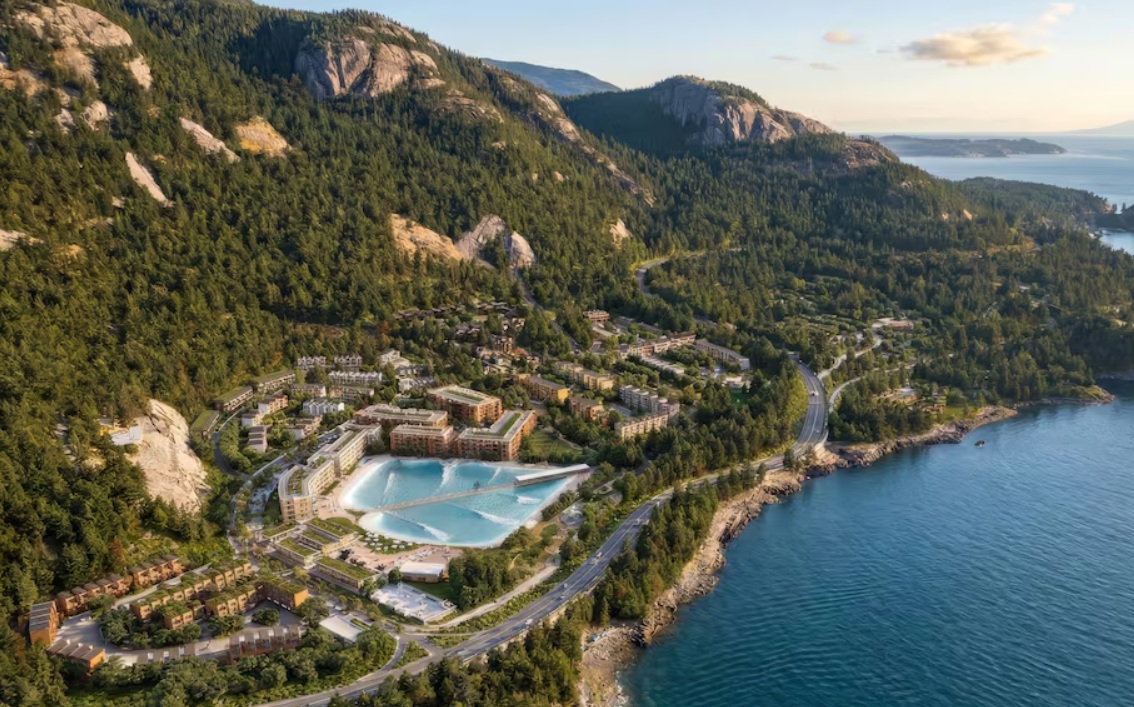 серф парк ванкувер | Наш Ванкувер Aerial view of a coastal resort town built into forested hills, with a large turquoise pool, apartment buildings, and winding roads along the shoreline.
