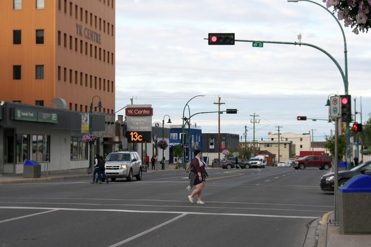 Crosswalk at a busy street with an orange YK Centre building on the left, traffic lights, and pedestrians crossing.