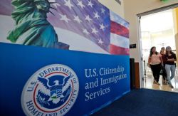 USCIS banner with Statue of Liberty and American flag, DHS seal, and 'U.S. Citizenship and Immigration Services' text; people entering through a doorway.