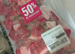 Ground beef package with a bright pink 50% off label showing in-store promotion.