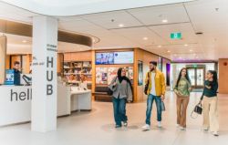 Group of students walking through a modern university lobby past the front desk in the student services area (Hub).
