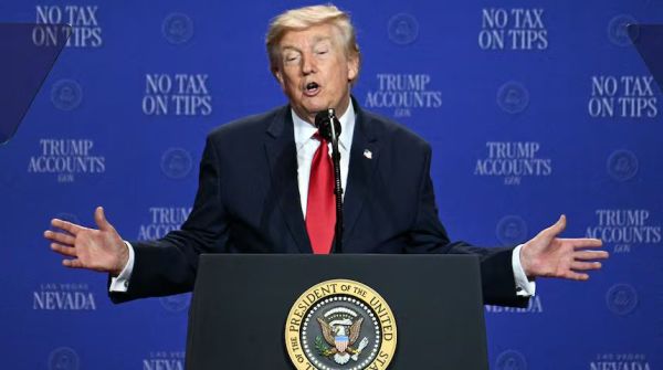 Man in a dark suit and red tie speaks from a podium with the presidential seal, arms outstretched, against a blue backdrop reading No Tax on Tips.