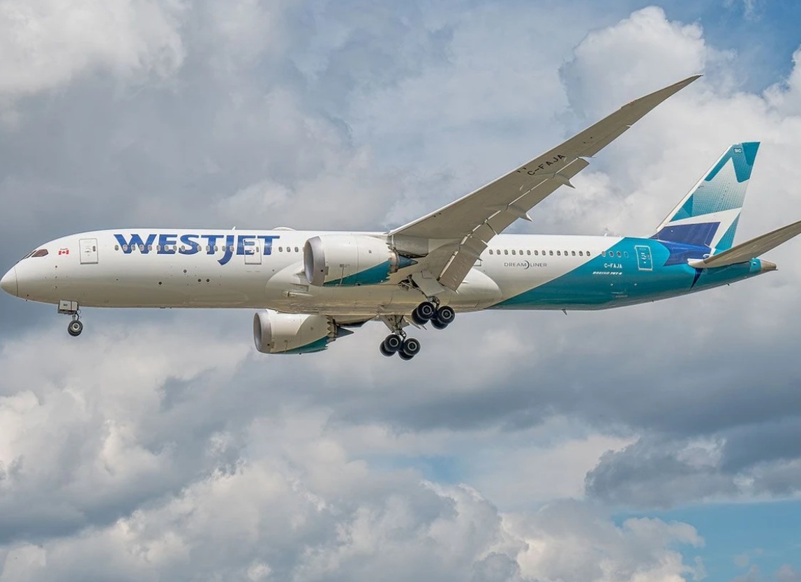 WestJet Boeing 787 Dreamliner in flight with landing gear down against a cloudy sky.