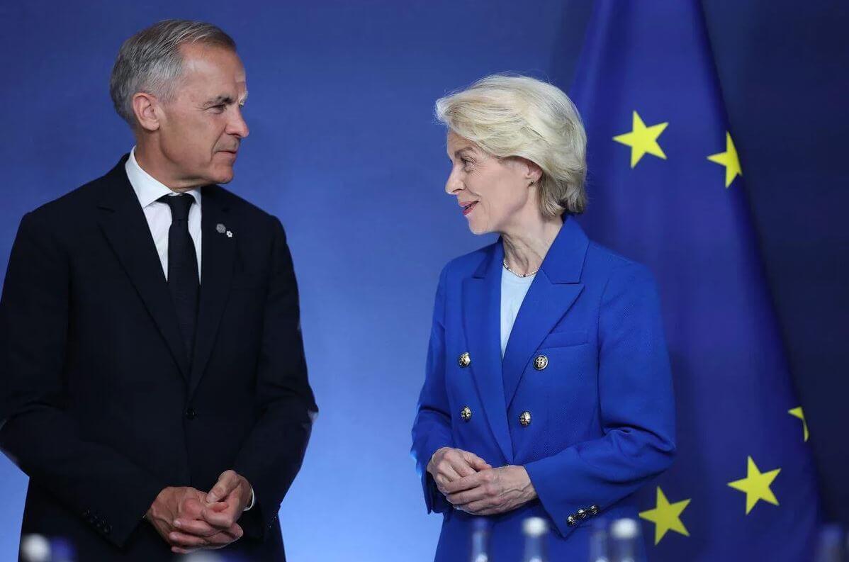 Евросоюз и Канада | Наш Ванкувер Two professionals in formal attire facing each other against a blue backdrop with EU flags in the background.
