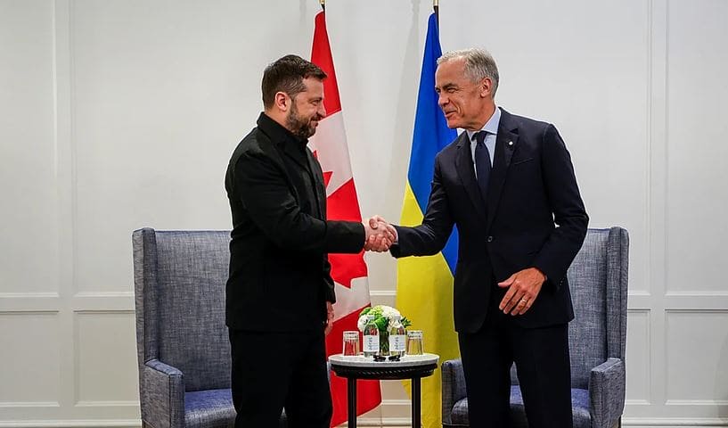Канада намерена присоединиться к кредиту | Наш Ванкувер Two men in suits shake hands in a formal room with Canadian and Ukrainian flags behind them.