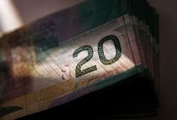Close-up of a stack of 20-euro banknotes fanned out in a dimly lit setting.