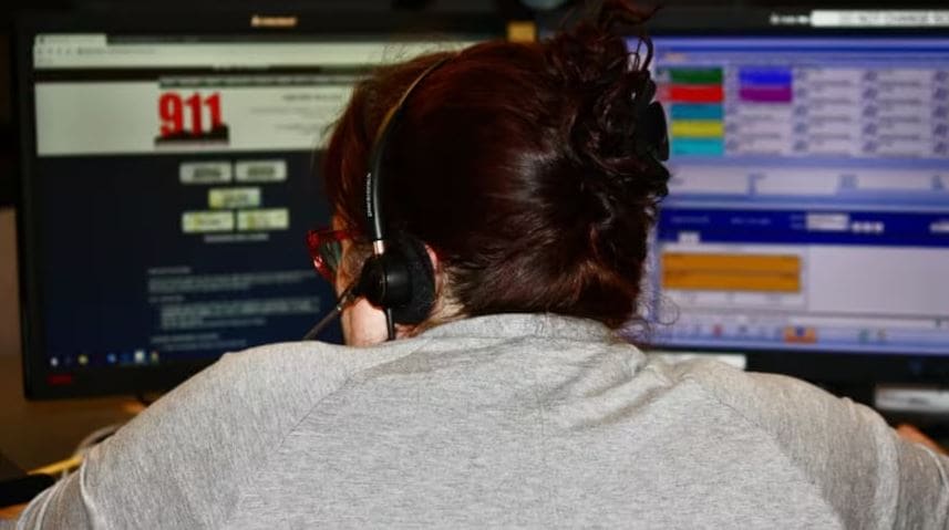 Масштабный сбой службы 911 | Наш Ванкувер Back view of an operator wearing a headset at a dual-monitor dispatch desk, monitoring emergency software.