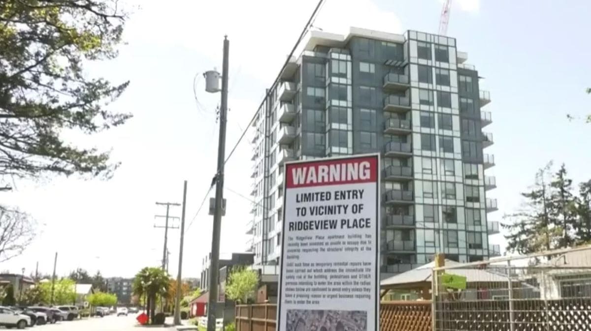 Construction site near a modern apartment building with a large WARNING sign about limited entry to Ridgeview Place in the foreground.