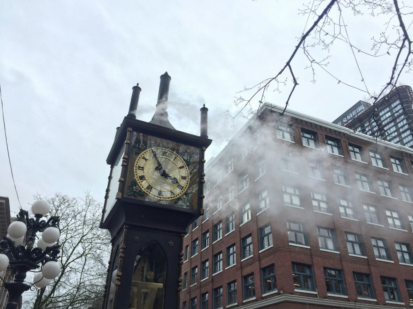 Часы Gastown Steam Clock на улице в Ванкувере днём, рядом прохожие и фасады старых зданий