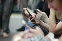 Подросток держит в руках смартфон, на экране которого видны иконки популярных социальных сетей