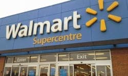 Покупательница с телефоном в проходе магазина Walmart пользуется ИИ-помощником Sparky