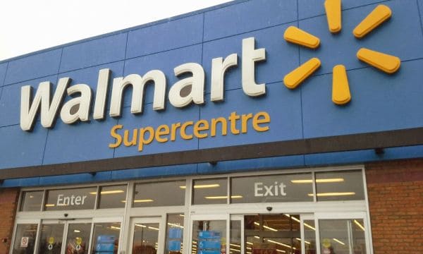 Покупательница с телефоном в проходе магазина Walmart пользуется ИИ-помощником Sparky