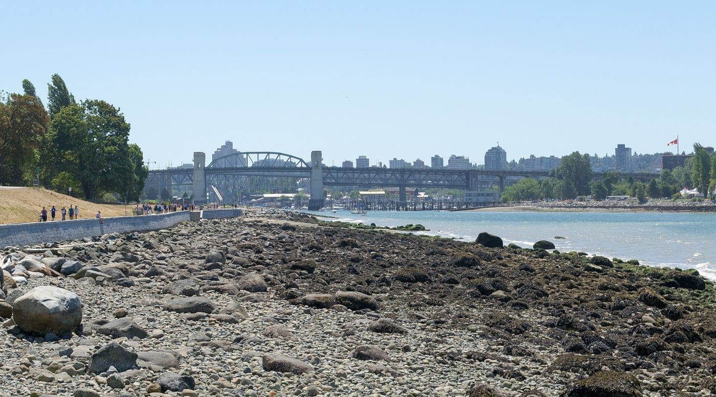 Закат над Ванкувером и бухтой English Bay зимой, на горизонте силуэты зданий и гор