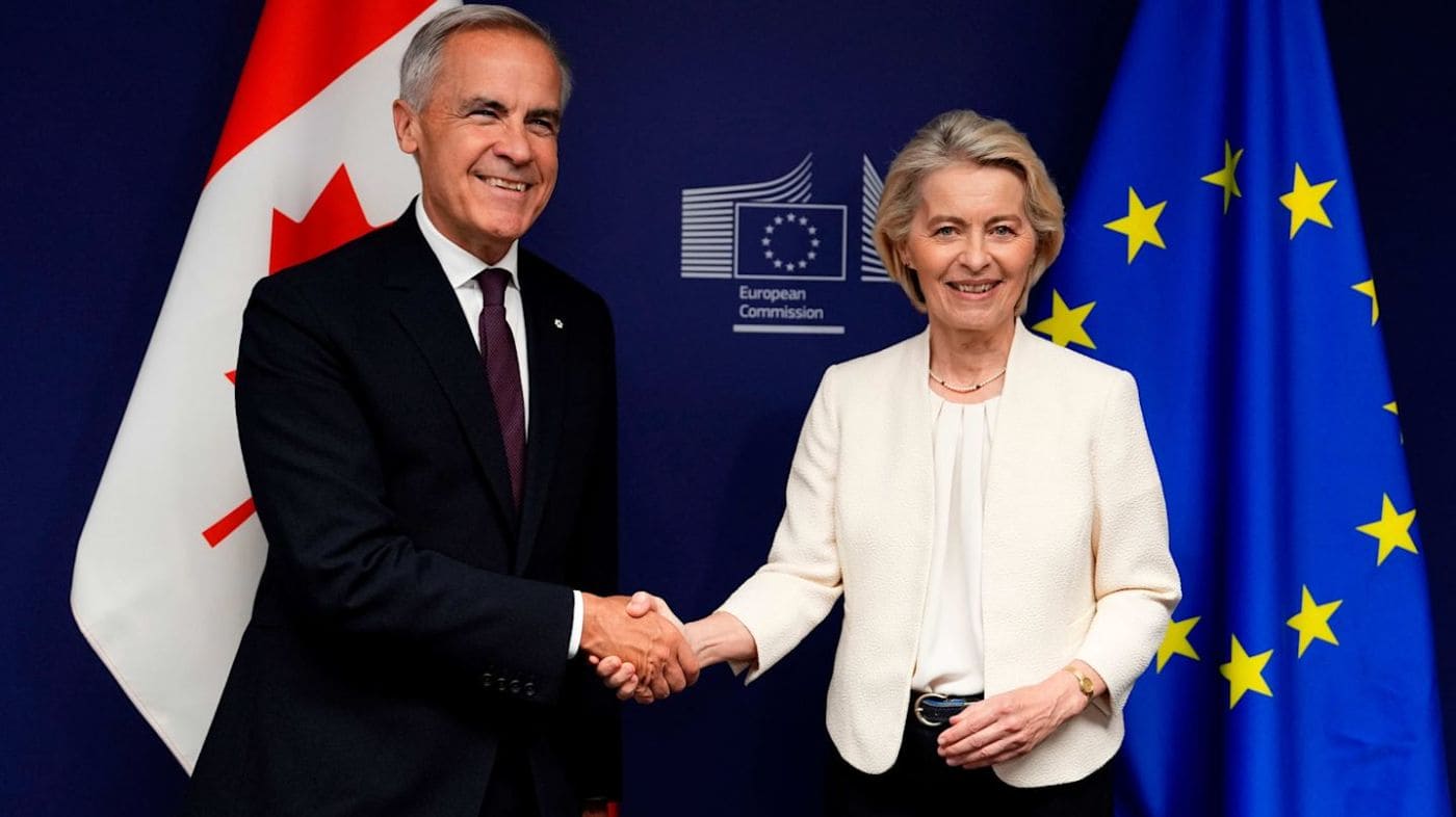 ассоциированное членство к 2027 году | Наш Ванкувер Two officials in formal attire shake hands in front of EU flags and a Canadian flag, with a European Commission backdrop.