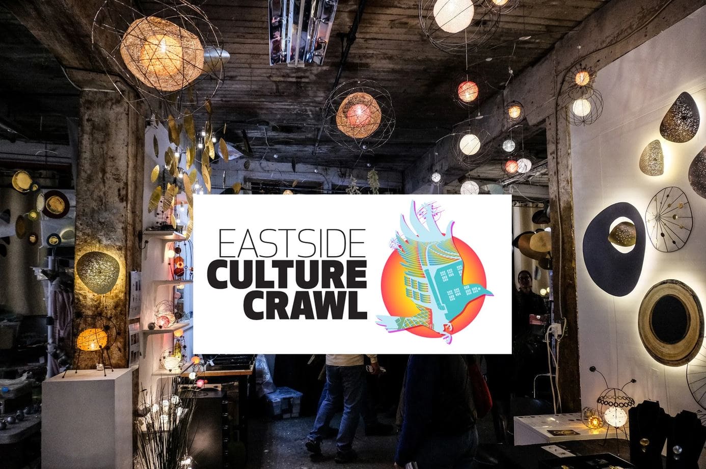 Banner reads 'EASTSIDE CULTURE CRAWL' with a colorful circular emblem; background shows an art/lighting shop filled with hanging lamps and shelves.