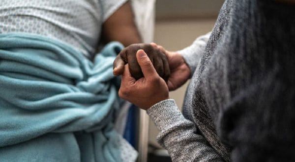 Two people hold hands in a comforting, supportive gesture.