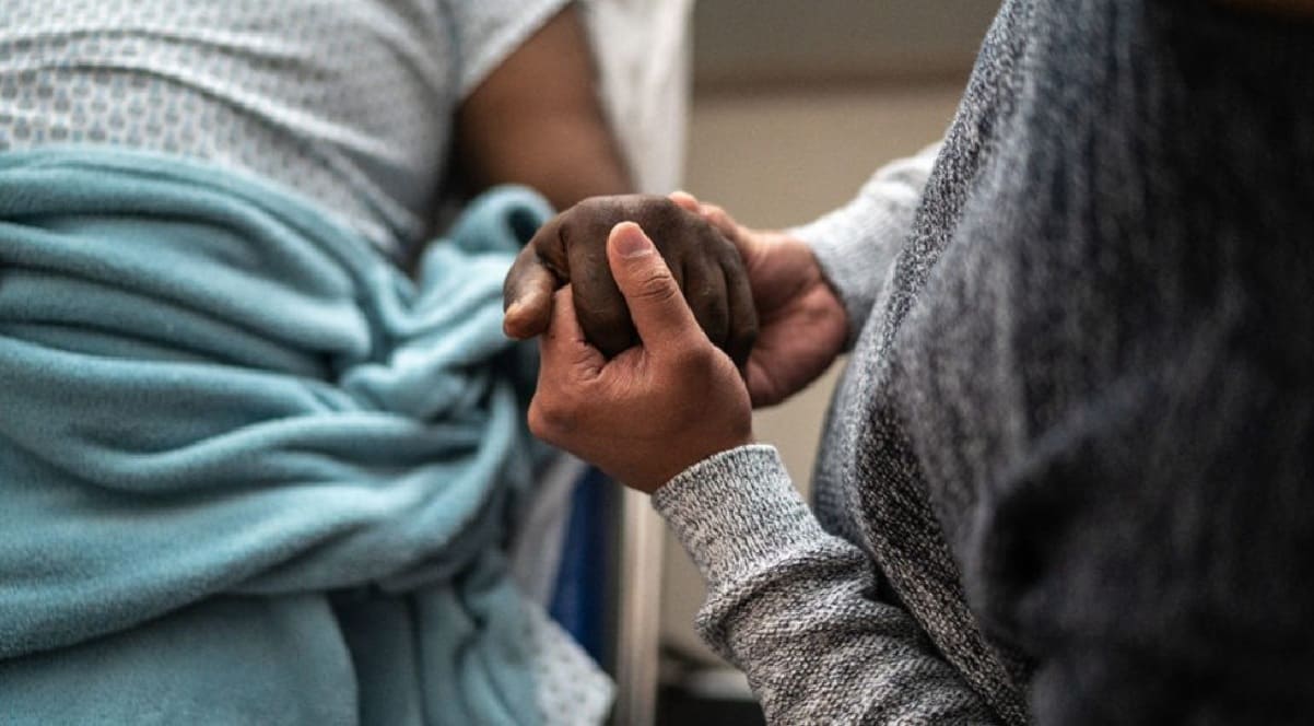 Two people hold hands in a comforting, supportive gesture.