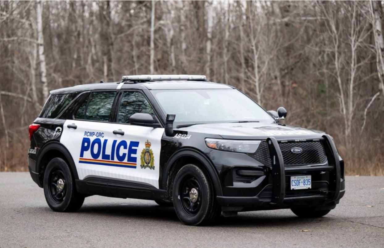 Canadian RCMP police SUV with POLICE logo parked on a road, wooded background, utility lights on roof.