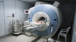 A large MRI scanner in a medical room with a patient’s feet visible on the table as they slide into the bore.