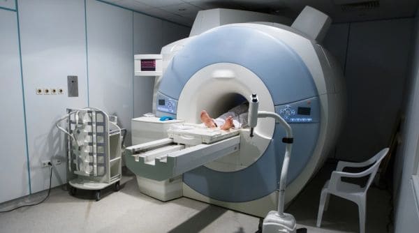 A large MRI scanner in a medical room with a patient’s feet visible on the table as they slide into the bore.