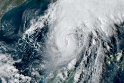 Satellite image of a powerful hurricane with a clear eye over the Atlantic near the U.S. coast, spiraling clouds and heavy storm bands.