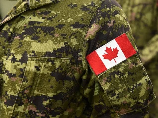 Close-up of a camouflaged military uniform with a Canadian flag patch on the sleeve.