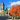 Parliament buildings with a bright blue sky and vibrant orange autumn trees in a city square.